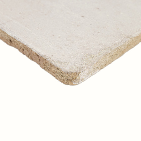 Un carreau de terre cuite beige clair et rugueux est incliné, révélant une surface texturée et mate et des bords légèrement irré