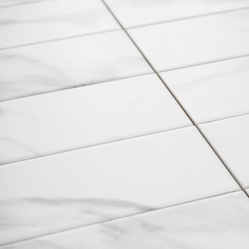 Rectangular white tiles with subtle gray veining are arranged in a grid pattern, resembling marble, suggesting a clean and elega