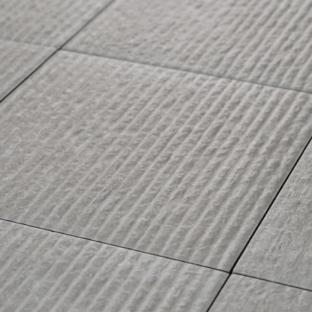 Una serie de azulejos de cerámica de color gris claro, texturizadas con crestas horizontales espaciadas uniformemente, forman un