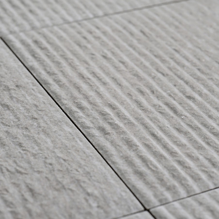 Los azulejos de cerámica grises están alineadas y presentan una superficie texturizada con ranuras lineales, creando un patrón s