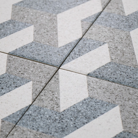 Los azulejos grises y blancos forman un patrón en zigzag, que se cruzan en las líneas de lechada, creando un diseño geométrico s Los azulejos grises y blancos forman un patrón en zigzag, que se cruzan en las líneas de lechada, creando un diseño geométrico s