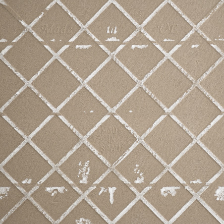 Un azulejo de cerámica beige muestra una cuadrícula de líneas blancas elevadas que se cruzan, formando formas de diamantes. El t