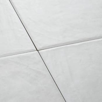 Cuatro azulejos de cerámica blanca forman un patrón cuadrado sin costuras, creando una superficie lisa y limpia en un ambiente m