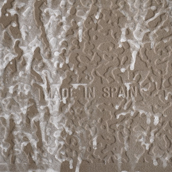 Azulejo marrom com padrões brancos texturizados que lembram ondas abstratas. O texto `MADE IN SPAIN` está gravado no centro.