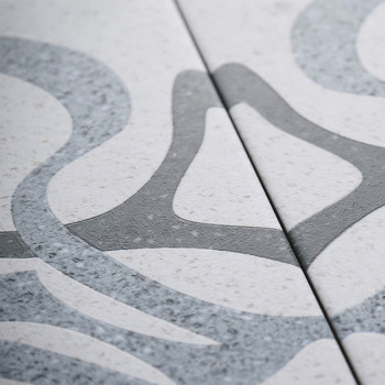 Dos azulejos de cerámica con patrones abstractos suaves y grises entrelazados que se muestran sobre un fondo moteado claro. Los 