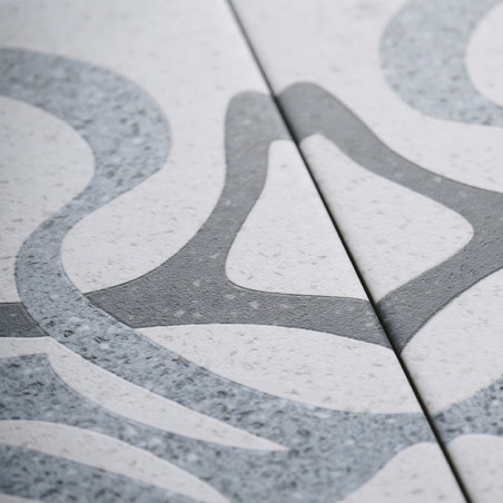 Dos azulejos de cerámica con patrones abstractos suaves y grises entrelazados que se muestran sobre un fondo moteado claro. Los Dos azulejos de cerámica con patrones abstractos suaves y grises entrelazados que se muestran sobre un fondo moteado claro. Los