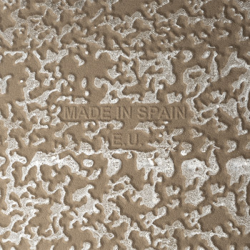 In reliëf aangebrachte tekst `MADE IN SPAIN` en `R.E.U.` verschijnt op een gestructureerd, gespikkeld oppervlak met onregelmatig