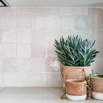 O backsplash de azulejos de terracota reflete a iluminação sob o armário em uma cozinha moderna, cercada por armários de madeira