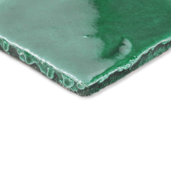 Glanzende groene terracotta tegel, schuin geplaatst in natuurlijk licht, met nadruk op de gladde, gebogen randen en het glanzend