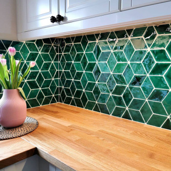 Green hexagonal tiles form a backsplash. A pink vase with tulips sits on a wooden countertop in a kitchen.