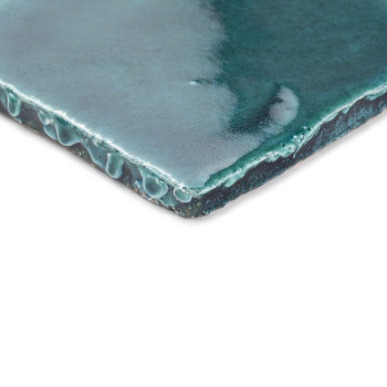 Een geglazuurde, groene terracotta tegel met een druipende textuur. rustend op een witte achtergrond, waarbij het glanzende oppe