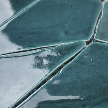 Les carreaux en terre cuite émaillée bleu-vert s'emboîtent, formant une surface inégale et réfléchissante avec des lignes de cou