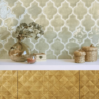 Un jarrón de vidrio con hojas secas se asienta sobre una superficie blanca, rodeado de cestas tejidas y con azulejos decorativos