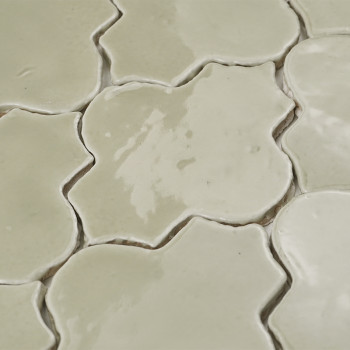 Vaso de vidro com folhas secas assenta sobre uma superfície branca, rodeado por cestos trançados, apoiados por azulejos decorati