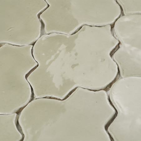 Les carreaux en terre cuite de couleur crème forment un motif floral, avec des surfaces brillantes réfléchissant la lumière dans