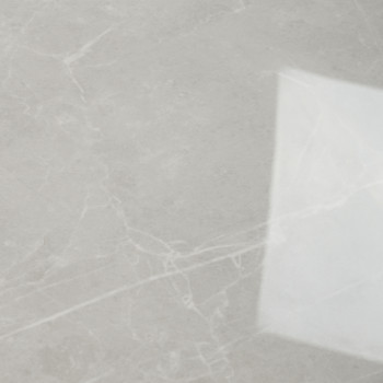 Una losa de mármol suave de color gris claro muestra patrones blancos en forma de vetas que cruzan su superficie. En el lado der