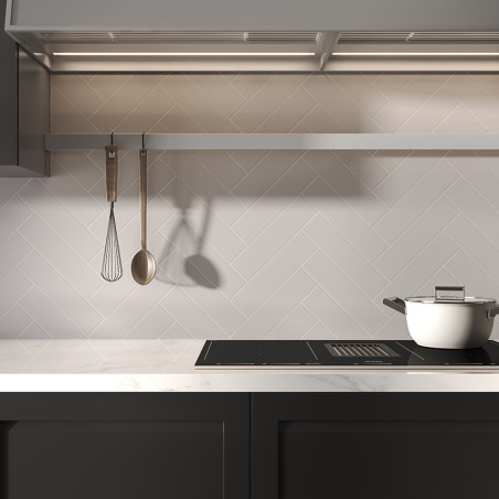 Een witte pot staat op een strak fornuis onder een rij hangend keukengerei in een moderne keuken met tegels met visgraatmotief. Een witte pot staat op een strak fornuis onder een rij hangend keukengerei in een moderne keuken met tegels met visgraatmotief.