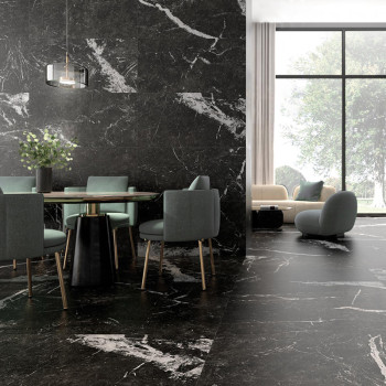 Un coin repas avec une table en verre et des chaises vertes repose sur un sol en marbre noir. A proximité, un coin salon cosy do