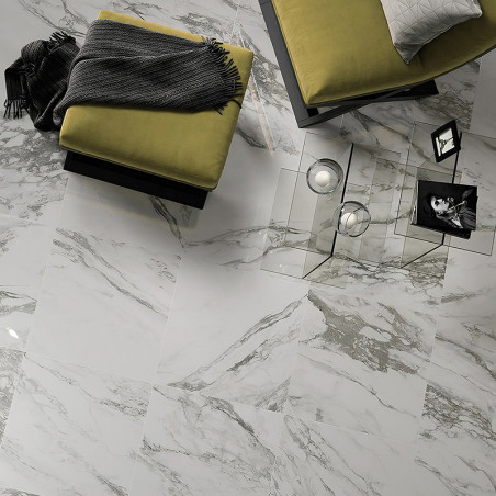 Tegels met marmermotief bedekken de vloer en reflecteren het licht. Twee olijfgroene hockers met grijze dekens en een glazen sal Tegels met marmermotief bedekken de vloer en reflecteren het licht. Twee olijfgroene hockers met grijze dekens en een glazen sal