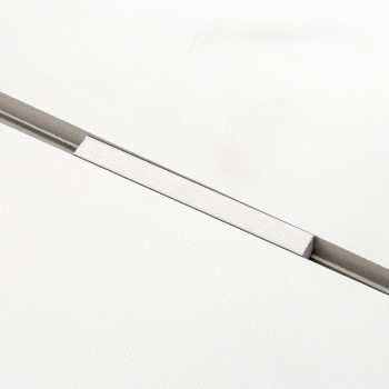 A white tile with a narrow, recessed rectangular groove bisecting it diagonally, creating a clean, minimalist appearance.