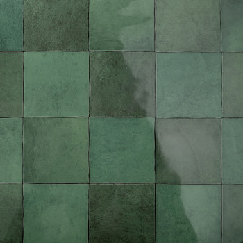 Los azulejos cuadrados verdes dispuestos en una cuadrícula reflejan la luz, creando una superficie brillante. Forman un patrón c
