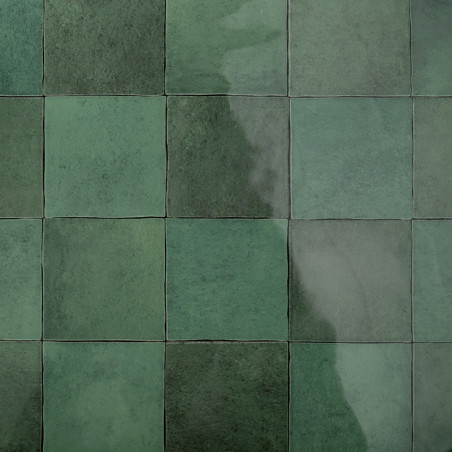 Groene vierkante tegels gerangschikt in een raster reflecteren het licht, waardoor een glanzend oppervlak ontstaat. Ze vormen ee