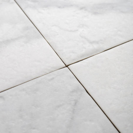 Les carreaux de marbre blanc forment un motif homogène, se croisant proprement au niveau des lignes diagonales. la texture est l