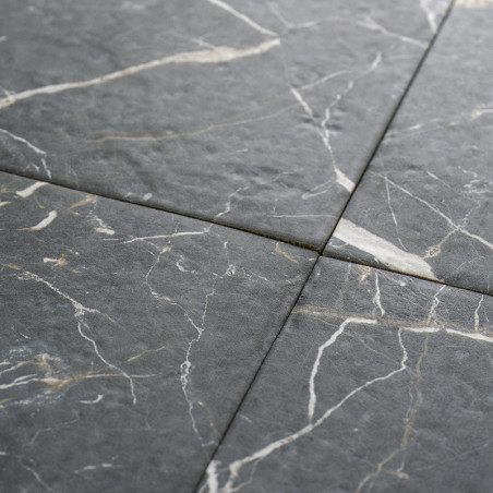 Quatre carreaux de pierre gris foncé se croisent, formant un motif en croix. Des veines blanches et gris clair traversent la sur