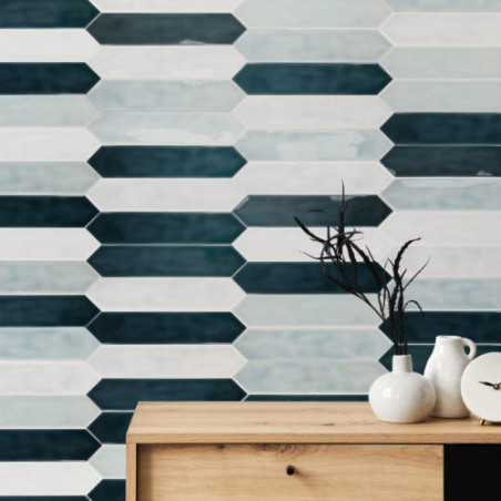 Una consola de madera con cerámico se encuentra frente a una pared de azulejos hexagonales alargados en diferentes tonos de azul