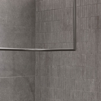 Des carreaux rectangulaires gris, alignés selon un motif en grille, forment un mur d'angle. Aucune ligne de coulis visible, créa