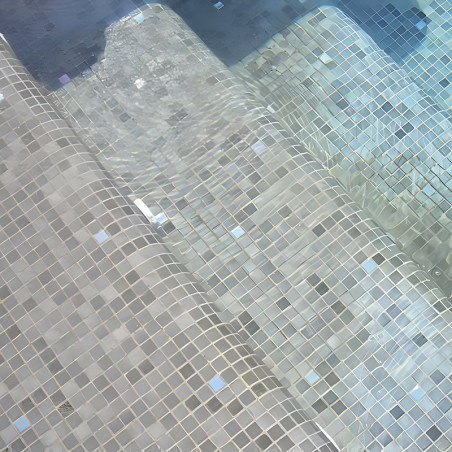 Glass tiles form steps submerged in shimmering pool water, creating a gradient effect transitioning from beige to turquoise.