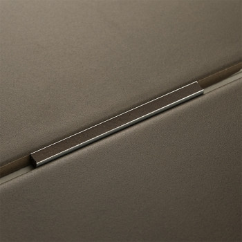 Une garniture métallique repose entre deux carreaux gris mat, formant une couture précise dans un design moderne et minimaliste.