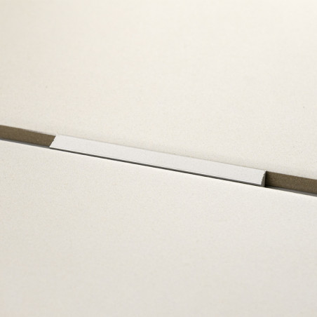 Eine rechteckige weiße Fliese liegt horizontal auf einer grauen Oberfläche mit einer dünnen Nut darunter und schafft so eine min Eine rechteckige weiße Fliese liegt horizontal auf einer grauen Oberfläche mit einer dünnen Nut darunter und schafft so eine min