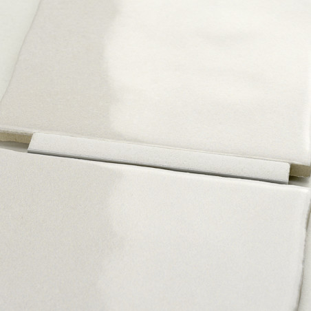Four overlapping, smooth, off-white ceramic tiles rest flatly on a surface, creating a uniform appearance with subtle texture va