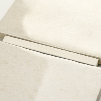 Un carreau rectangulaire beige repose sur une pile de carreaux similaires, créant un motif soigné et ordonné dans un cadre neutr