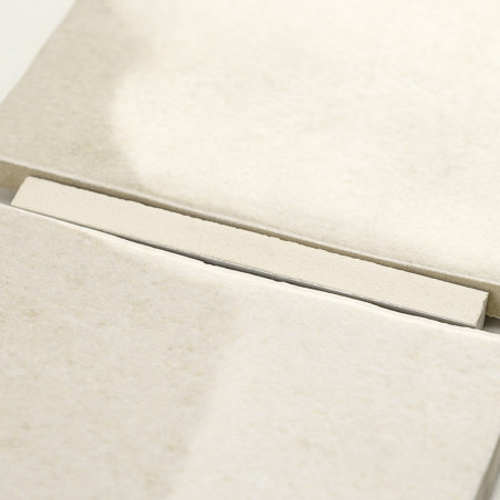 Um ladrilho retangular bege repousa sobre uma pilha de ladrilhos semelhantes, criando um padrão elegante e ordenado em um ambien