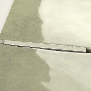 Zwei benachbarte Fliesen treffen auf einen dünnen Metallstreifen, der sie trennt. Die Fliesen haben eine verlaufende Textur, die