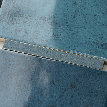 Les carreaux de céramique aux surfaces texturées et dégradées de bleu sont superposés et disposés, mettant en valeur les nuances