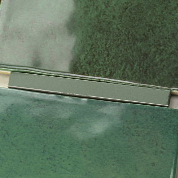 Green ceramic tiles with a glossy finish overlap slightly, showcasing variations of dark and light green hues, forming a texture