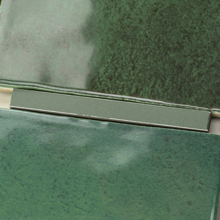 Green ceramic tiles with a glossy finish overlap slightly, showcasing variations of dark and light green hues, forming a texture