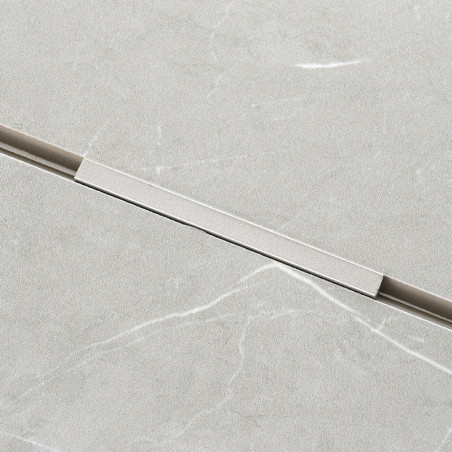 Un carreau rectangulaire gris clair présente un motif de marbre subtil avec de légères veines blanches. Une fine bande métalliqu