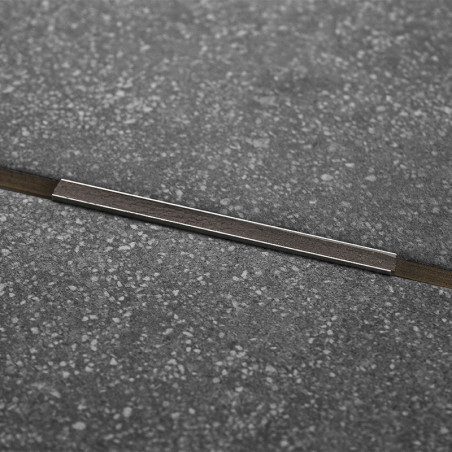 A dark gray, speckled tile features a thin metallic strip running diagonally across its center, enhancing a modern, industrial d
