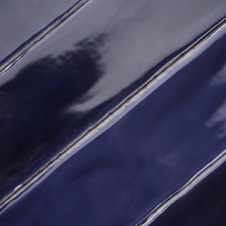 Les carreaux bleu marine brillants et ondulés alignés en diagonale créent une surface lisse et réfléchissante avec de subtiles v