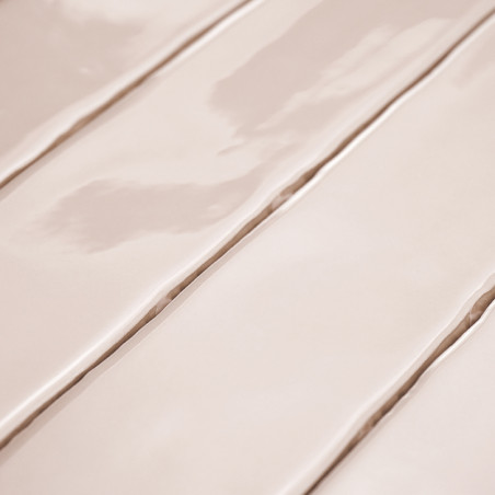 Glänzende, beige Keramikfliesen liegen nebeneinander und reflektieren das Licht. Die sichtbaren Nähte verlaufen in Längsrichtung