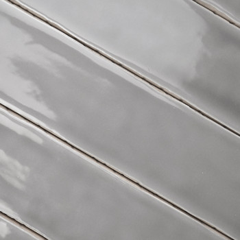 Os ladrilhos cerâmicos cinza são dispostos diagonalmente, refletindo a luz com acabamento brilhante, alinhados com finas linhas 