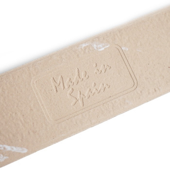 O ladrilho retangular bege exibe o texto em relevo “Made in Spain”, cercado por sutis manchas brancas, deitado sobre um fundo br