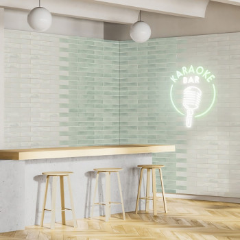 Um ambiente de bar minimalista apresenta três bancos de madeira em um balcão de concreto. Um letreiro de néon diz “KARAOKE BAR” 