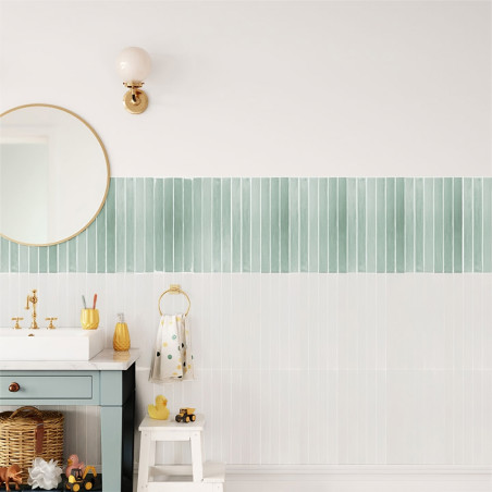 O banheiro apresenta azulejos listrados verdes decorando a parede. Abaixo, uma pia com torneira dourada fica ao lado de um espel O banheiro apresenta azulejos listrados verdes decorando a parede. Abaixo, uma pia com torneira dourada fica ao lado de um espel