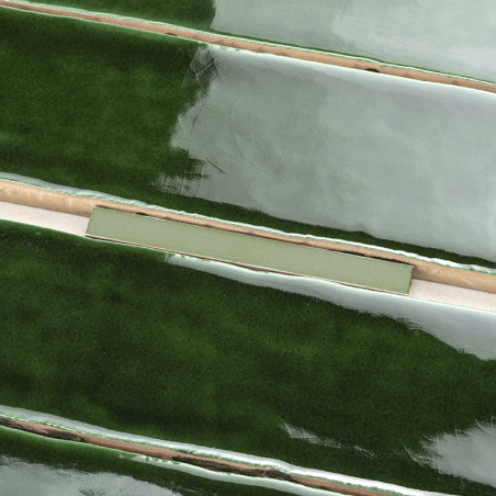 Glossy green tiles are arranged horizontally, with one tile missing, revealing a light beige base beneath. The setting appears i Glossy green tiles are arranged horizontally, with one tile missing, revealing a light beige base beneath. The setting appears i