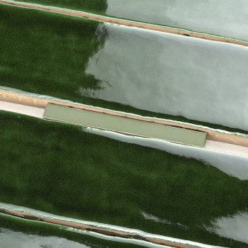 Glanzende, langwerpige groene tegels liggen horizontaal met gladde, reflecterende oppervlakken, gescheiden door dunne beige voeg